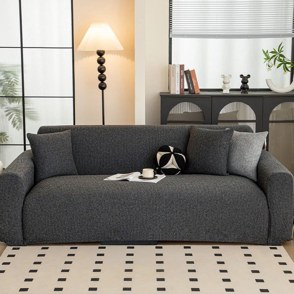 Charcoal knit sofa cover styled in a bright living room with floor lamp and patterned rug