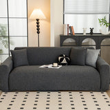 Charcoal knit sofa cover styled in a bright living room with floor lamp and patterned rug