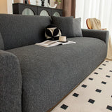 Angled close-up of charcoal knit sofa cover with matching cushions and coffee cup