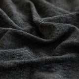 Macro of charcoal knit fabric showing heathered twill texture and soft folds
