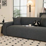 Angled view of charcoal knit sofa cover in a lounge with floor lamp and black and white cushion