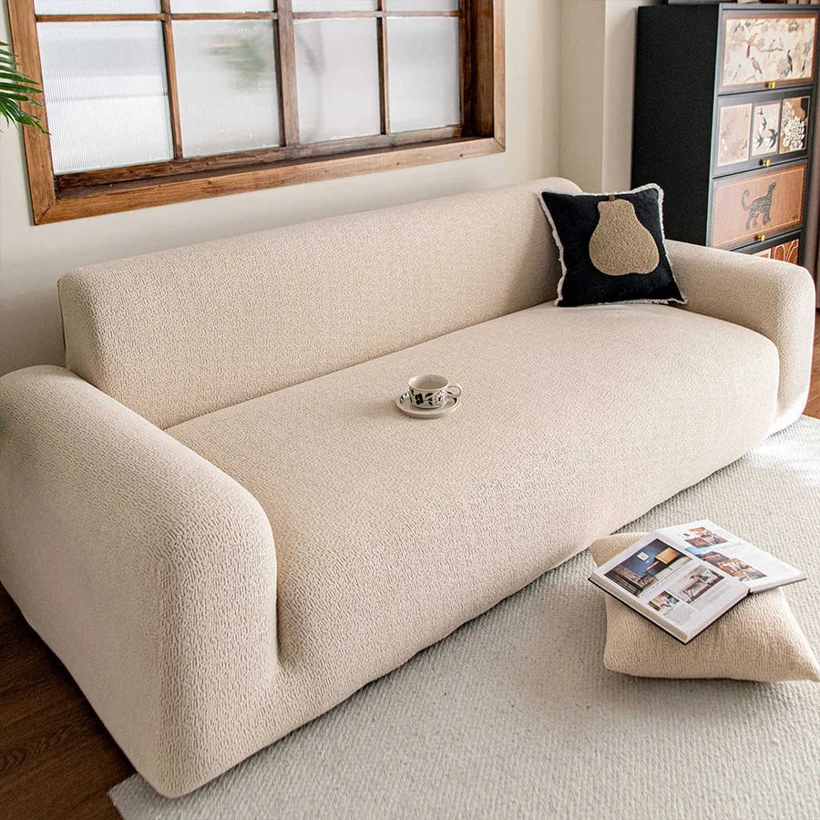 Cream beige knit sofa cover by a wooden window with black cushion and coffee cup