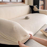Hands stretching the cream beige knit cover over an armrest to show its stretch fit