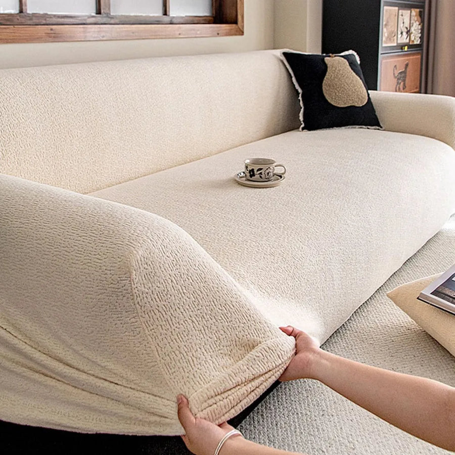 Hands stretching the cream beige knit cover over an armrest to show its stretch fit