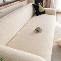 Angled close-up of cream beige knit sofa cover seat with black cushion and coffee cup