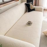 Angled close-up of cream beige knit sofa cover seat with black cushion and coffee cup