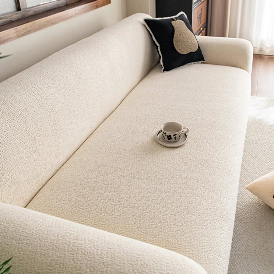 Angled close-up of cream beige knit sofa cover seat with black cushion and coffee cup
