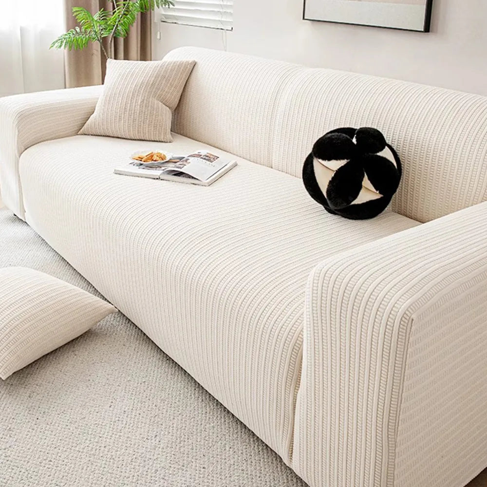 Angled view of cream ivory knit sofa cover with black and white cushion and open magazine