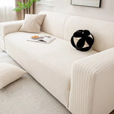 Angled view of cream ivory knit sofa cover with black and white cushion and open magazine