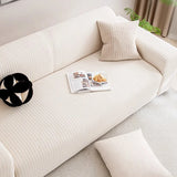 Overhead view of cream ivory knit sofa cover seat with open magazine and knot cushion