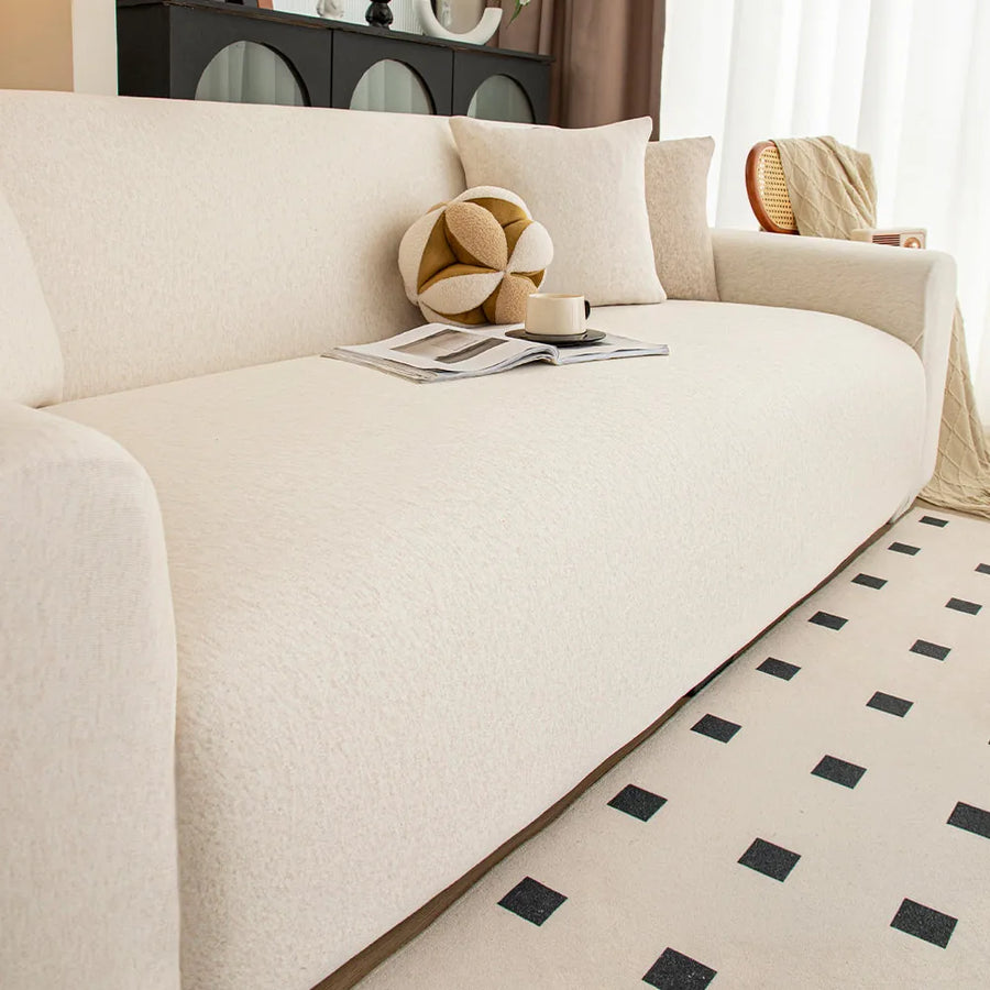 Close-up of cream linen knit sofa cover seat with decorative cushions and open magazine