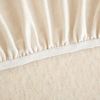 Detail of the elastic hem edge and woven underside of the cream linen knit cover