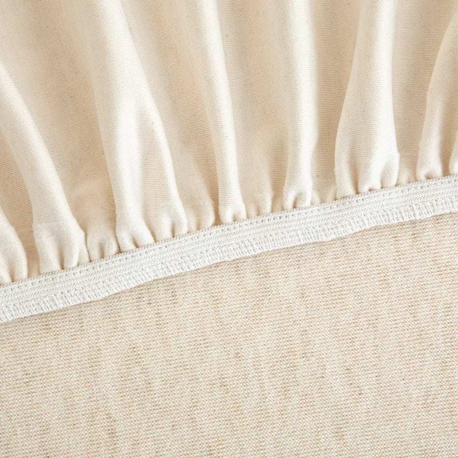 Detail of the elastic hem edge and woven underside of the cream linen knit cover