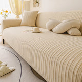 Angled close-up of honey taupe knit sofa cover with white knot cushion and coffee cup
