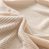 Macro of ivory sand knit fabric revealing diagonal ribbed texture and soft folds