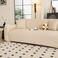 Angled view of the sand beige knit seat and armrest styled with a cushion and cup by a window.