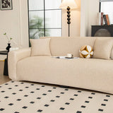 Angled view of the sand beige knit seat and armrest styled with a cushion and cup by a window.