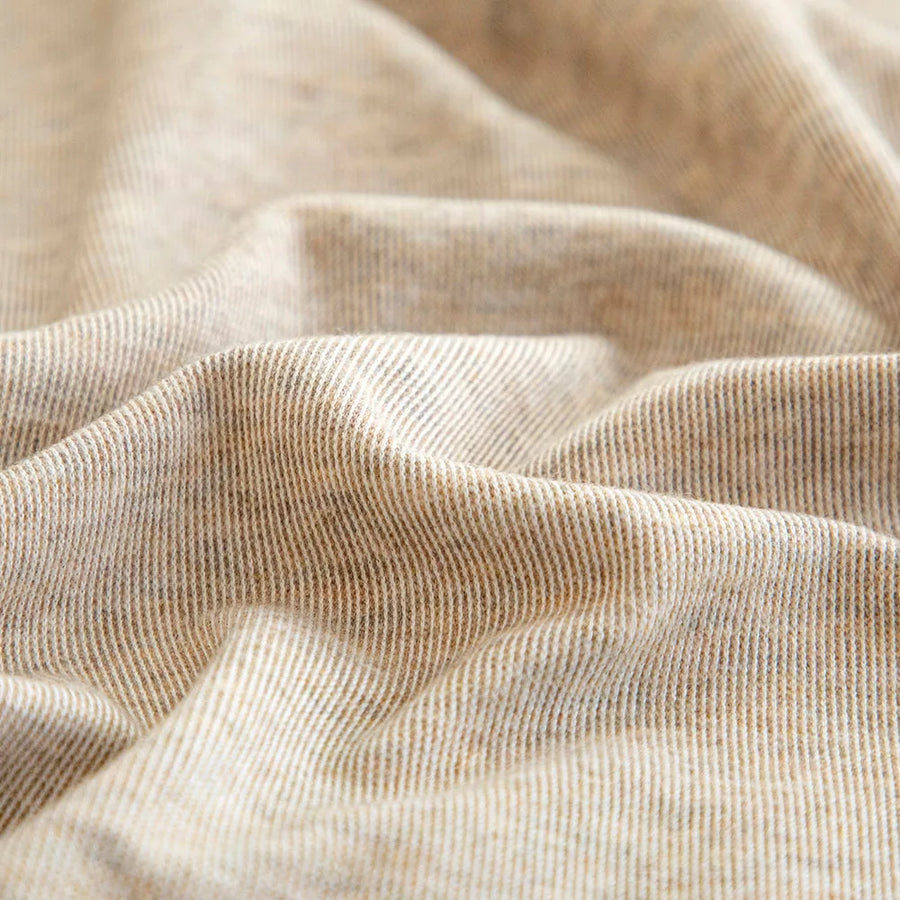 Macro of the sand beige knit texture with fine flecked striations draped in soft folds.