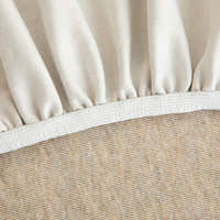 Detail of the elasticated hem and white band beneath the sand beige knit cover.