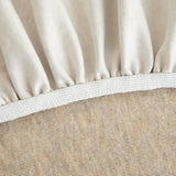 Detail of the elasticated hem and white band beneath the sand beige knit cover.