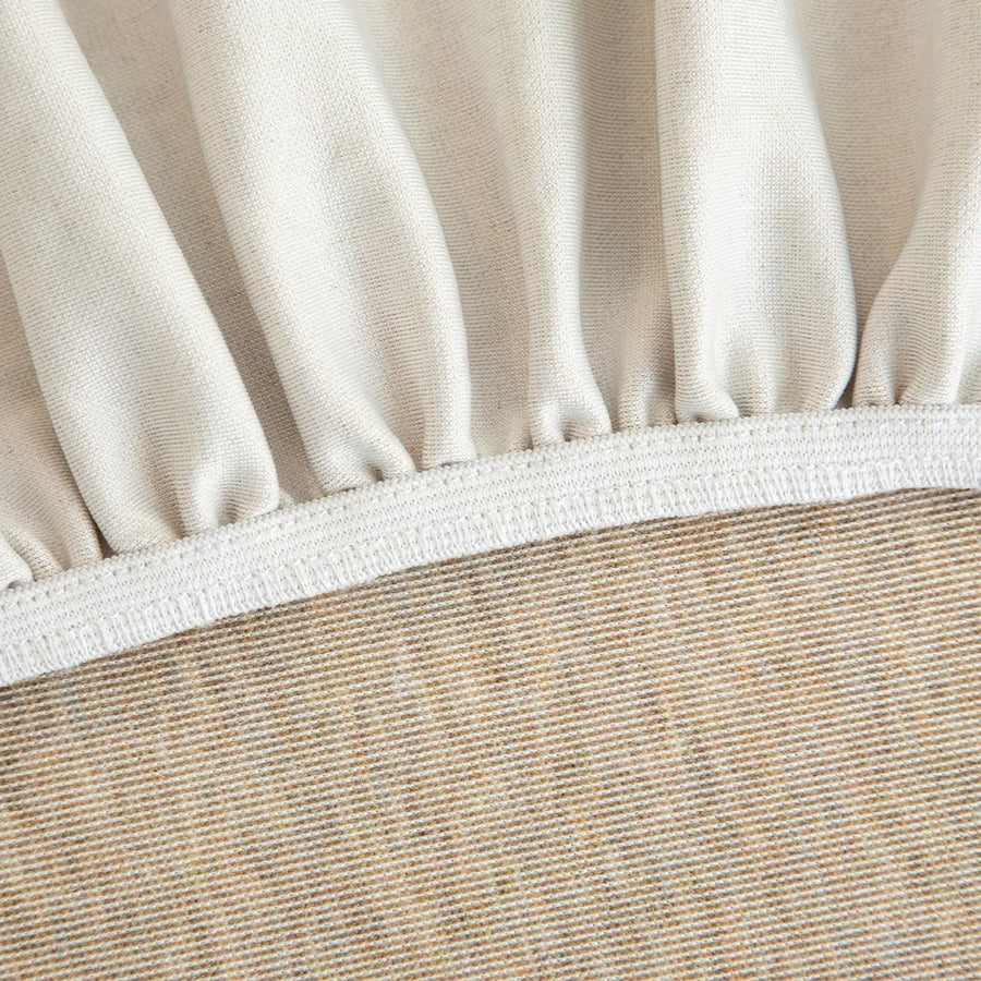 Detail of the elasticated hem and white band beneath the sand beige knit cover.