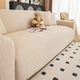 Angled living room view of the sand beige knit seat with a ball cushion, magazine and cup.