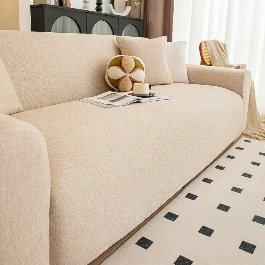 Angled living room view of the sand beige knit seat with a ball cushion, magazine and cup.