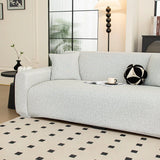 Angled view of silver grey knit sofa cover in a sunlit room with black and white cushion