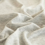 Macro of soft silver grey knit fabric showing fine striped weave and gentle folds
