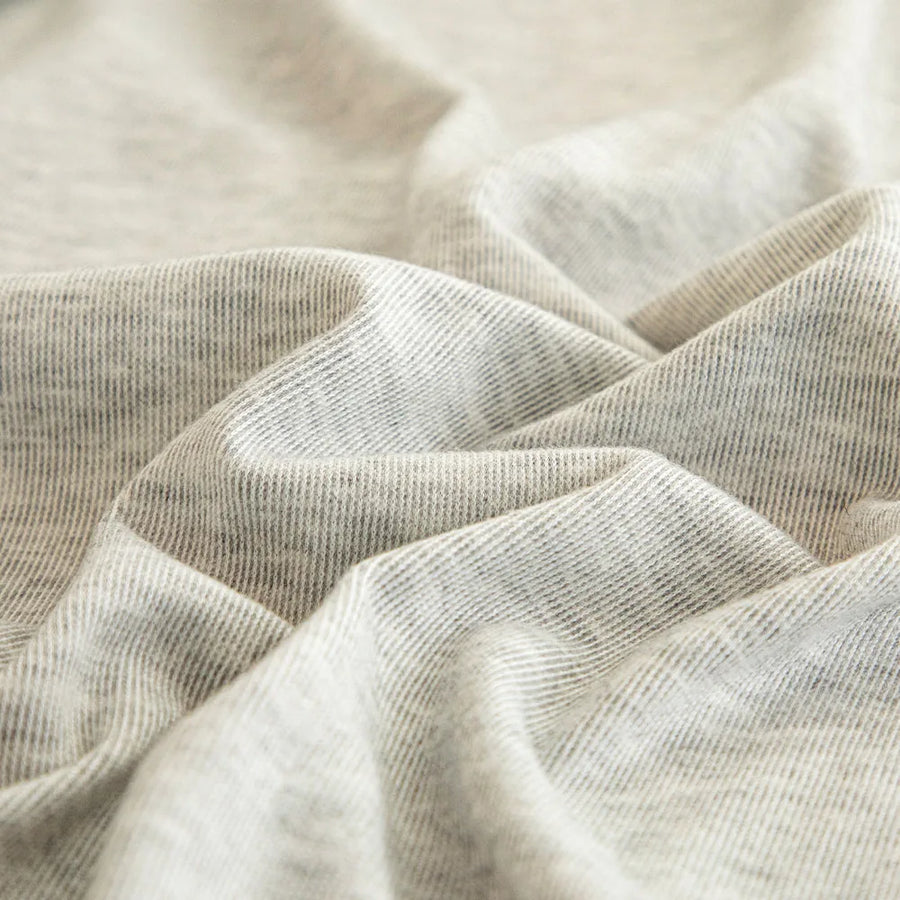 Macro of soft silver grey knit fabric showing fine striped weave and gentle folds