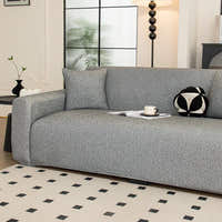 Angled view of the stone grey knit seat and armrest styled with a cushion and cup by a window.