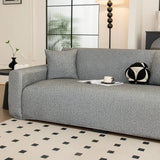 Angled view of the stone grey knit seat and armrest styled with a cushion and cup by a window.