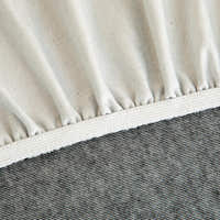 Detail of the elasticated hem and white band beneath the stone grey knit cover.