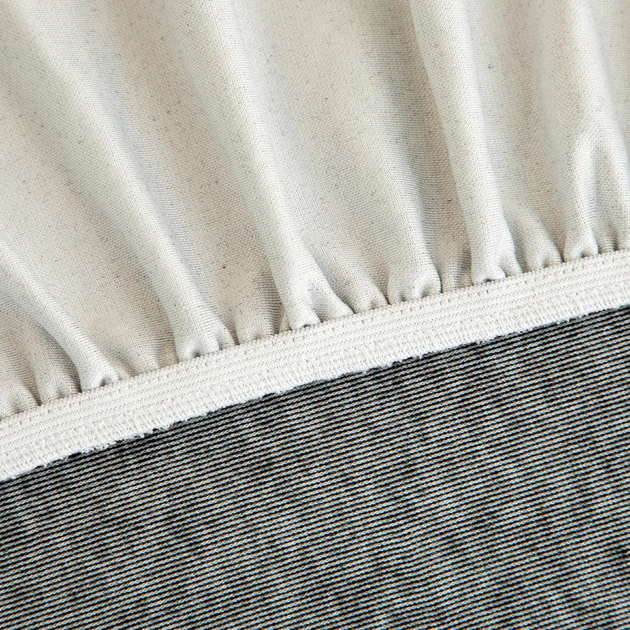 Detail of the elasticated hem and white band beneath the stone grey knit cover.