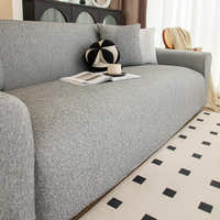 Angled living room view of the stone grey knit seat with a ball cushion, magazine and cup.