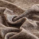 Macro of the warm taupe knit texture with fine striations draped in soft folds.