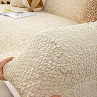 Hand lifting the cream ivory quilted cover corner to show its stretchy fit over the armrest.