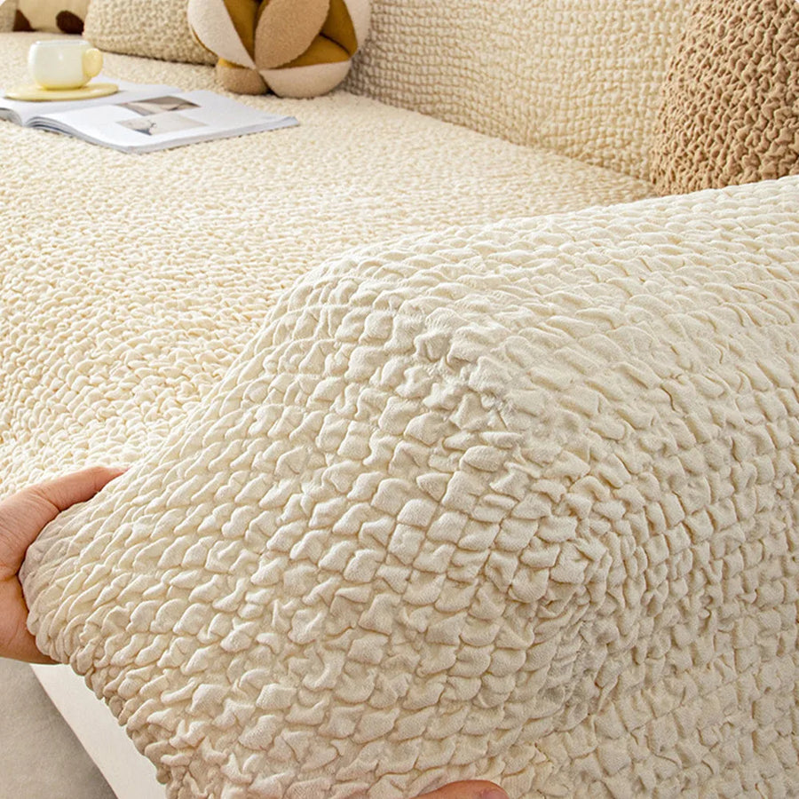Hand lifting the cream ivory quilted cover corner to show its stretchy fit over the armrest.