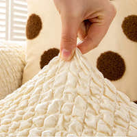 Fingers pinching the cream ivory quilted fabric, highlighting its puckered bubble texture.