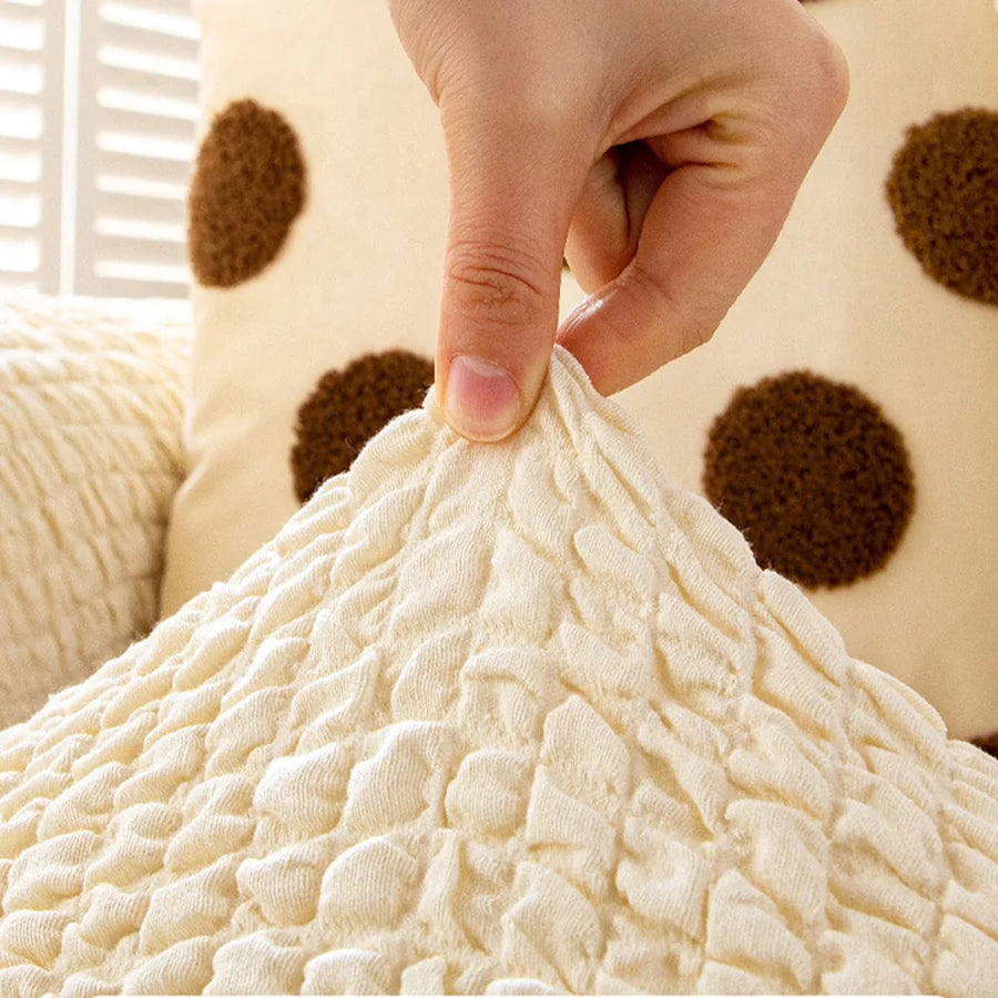 Fingers pinching the cream ivory quilted fabric, highlighting its puckered bubble texture.