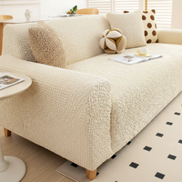 Angled living room view of a sofa in cream ivory quilted cover with bolster and cushions.