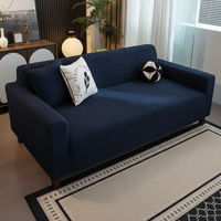 Sofa dressed in midnight navy quilted cover in a living room, angled view with printed and ball cushions.