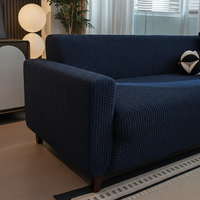 Midnight navy quilted cover wrapping a sofa armrest and wooden leg in a bright living room.