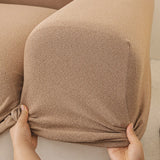 Hands stretching the caramel sand cover snugly around a rounded sofa armrest corner.