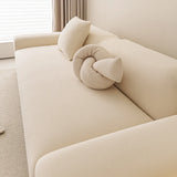 Angled view of the cream smooth sofa cover with a knot cushion by a window