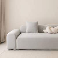 Silver grey smooth stretch sofa cover styled on a corner sofa with a cushion and knot pillow