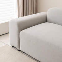 Corner of the silver grey smooth sofa cover by a window with sheer curtains