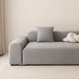 Stone grey smooth stretch sofa cover styled on a corner sofa with a cushion in a calm room