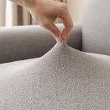 Hand stretching the stone grey sofa cover to show its flexible fit