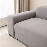 Close-up of the stone grey smooth sofa cover wrapping the armrest by a window